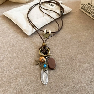 Detail view of ethnic vintage necklace with feather pendant and turquoise beads on fabric
