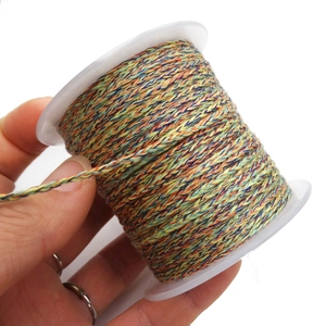 Close-up of colorful braided cord on a white spool for DIY jewelry making and crafts