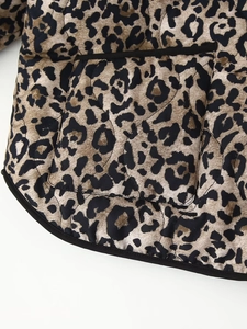 Detail view of leopard print quilted jacket featuring black piping and a functional patch pocket