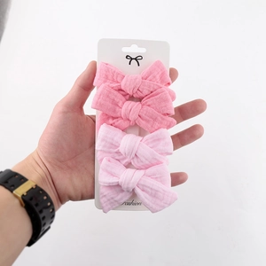 Detail of 4-piece pink fabric bow hair clips for kids on a white fashion display card