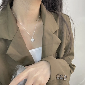 Detail showing an embossed evil eye pendant in 925 sterling silver worn by a model