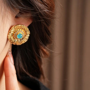 Close-up of vintage gold floral earrings with sky blue stone and pavé zircon on model
