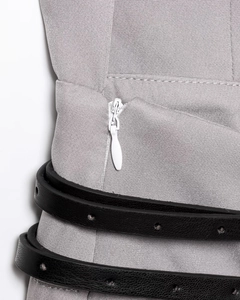 Detail view of grey fabric texture with white hidden zipper and black leather belt accent