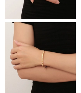 Macro shot of gold diamond-encrusted square link bracelet on model's wrist detail