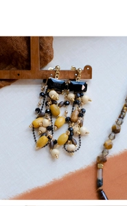Detailed view of bohemian wood bead earrings and necklace on wooden display stand