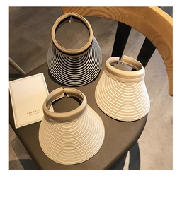 Detailed shot of three striped straw sun visors with open top design on a grey chair