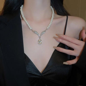 Close-up of pearl necklace featuring a diamond-encrusted V-shape and pear-cut pendant