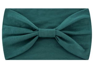 Close-up of a wide dark green knitted headband featuring a large central bow detail