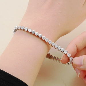 Dettaglio di un bracciale tennis con zirconi a forma di cuore indossato sul polso donna
