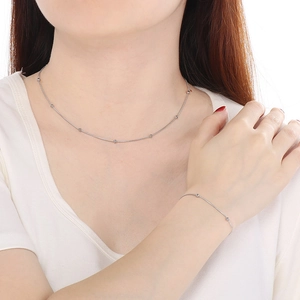 Gros plan sur un collier et bracelet minimalistes en acier inoxydable argenté avec perles