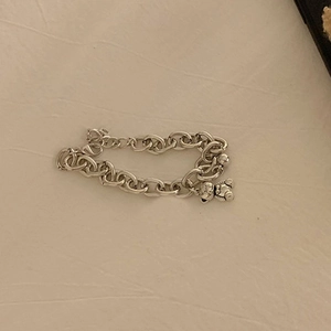 Polished S925 sterling silver chain bracelet with cute bear and bead charm on beige fabric