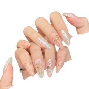 Handmade pink almond press-on nails with 3D gold bows and pearl accents