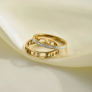 Close-up of two-in-one titanium steel rings with Roman numerals and diamond inlay on silk