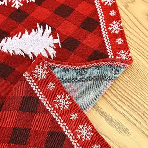 Close-up of red and black buffalo plaid knitted Christmas table runner with snowflake patterns