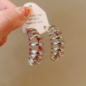 Detail of silver S925 minimalist spiral hoop earrings held on a display card