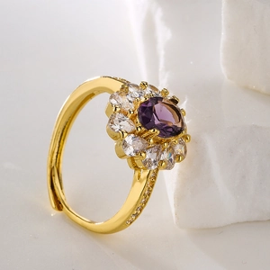 Macro shot of gold-plated cluster ring with purple oval gemstone and white cubic zirconia