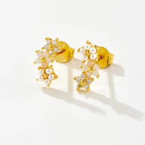 Macro detail of gold flower earrings with pearls, crystals, and S925 silver hallmarks