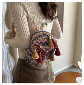 Detail of bohemian mini backpack with colorful geometric weaving and vibrant tassels