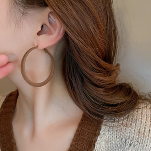 Detail of large chocolate brown flocked hoop earrings worn on model for a vintage look