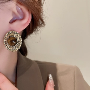 Close-up of vintage gold hammered earrings with brown tiger eye stone on a model
