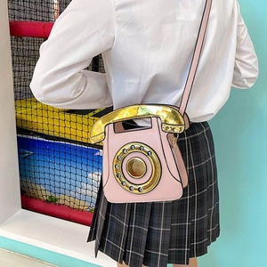 Close-up of pink vintage telephone crossbody bag with numeric dial and golden metal hardware
