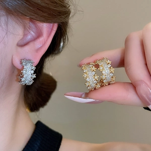 Detail showing crystal-encrusted flower C-shape stud earrings on model in gold and silver