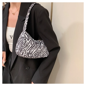 Détail du sac sous le bras en toile à motif zèbre porté avec un blazer noir élégant