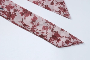 Detailaufnahme der rotbraunen Chiffonbänder mit Blumenmuster und spitzen Enden