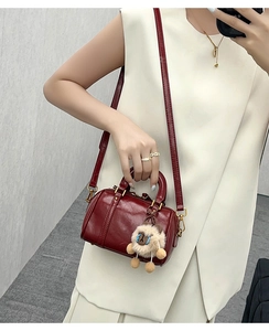 Detail of burgundy leather Boston bag with plush lamb charm and adjustable shoulder strap