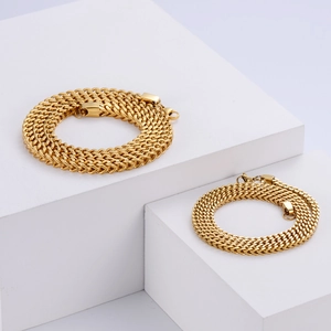 Gold Franco chain necklaces in two thicknesses on white geometric blocks over grey background
