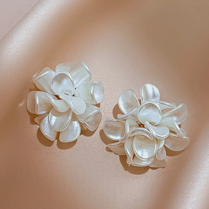 Detail view of white acrylic flower earrings with pearlescent finish on satin fabric