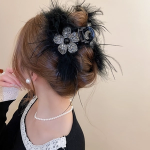 Détail d'une pince à cheveux élégante en plumes noires avec fleurs en cristal brillant