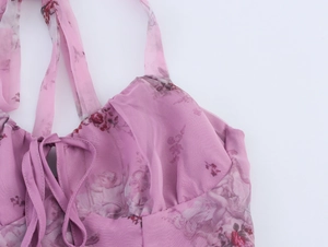 Close-up detail of pink floral organza fabric with ribbon tie and ruffled textures