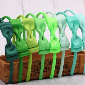 Simple grosgrain ribbon bow headbands in various green shades on a vintage wooden box