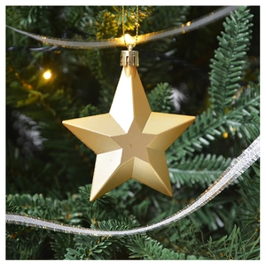 Close-up of a shiny gold star ornament hanging on a Christmas tree with warm lights