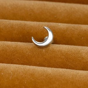 Macro shot of polished silver crescent moon stud earring on brown velvet display stand