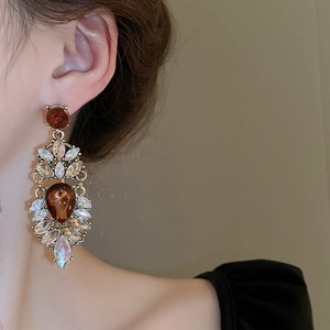 Macro detail of amber teardrop earring with colorful rhinestones on a female model