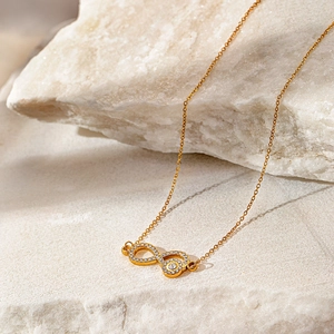 Macro detail of gold infinity necklace with white cubic zirconia on a natural white stone