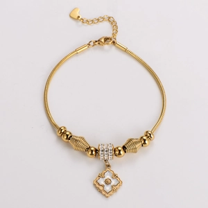 Macro shot of gold-plated beaded bracelet featuring a flower pendant with shell inlay