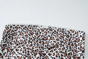 Détail d'un crop top léopard avec bordure en dentelle blanche et petit nœud