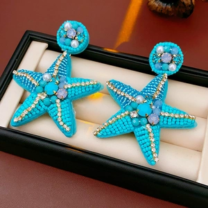 Detailed view of handmade beaded starfish earrings with blue gems and white pearls