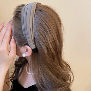 Gros plan d'un serre-tête plissé en satin gris sur un modèle avec bijoux en perles