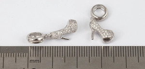 Detailed view of silver stiletto heel pendants with scale ruler for size reference