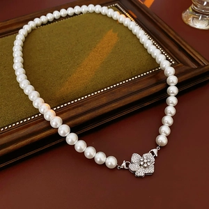 Macro shot of faux pearl necklace with zircon flower buckle on a vintage wooden frame