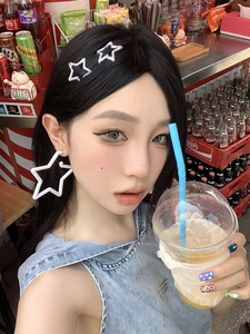 On-ear lifestyle shot of white acrylic star earrings and silver star clip in casual style