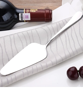 Polished stainless steel cake server with serrated edge on elegant napkin