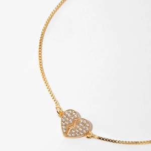 Macro shot of gold box chain bracelet with heart pendant and white zircon micro-inlay