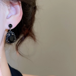 Close-up of model wearing black teardrop rhinestone earrings in a luxury jewelry set