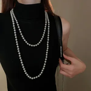 Detail of layered long faux pearl necklace with metallic grey finish on a model