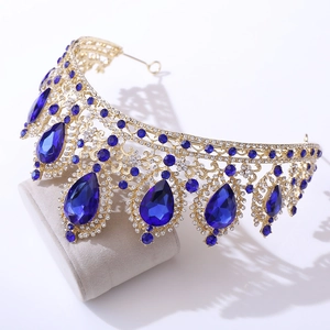 Detailed shot of golden crown featuring large blue teardrop gems and clear rhinestones